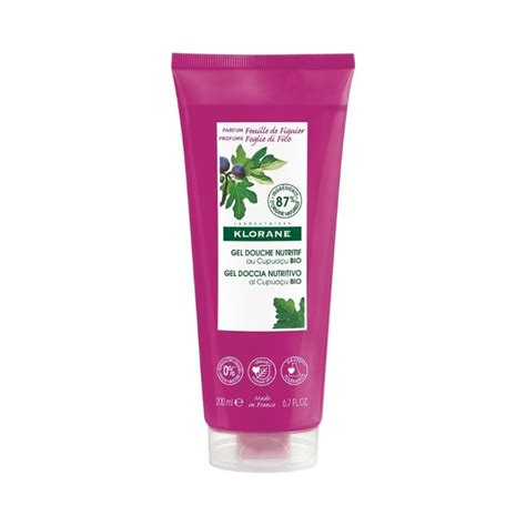 une bouteille de gel douche Klorane Feuille de Figuier posée sur un rebord de baignoire avec des feuilles de figuier en arrière-plan
