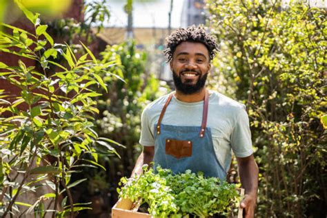 Personne souriante dans une jardinerie, tenant un outil de jardinage