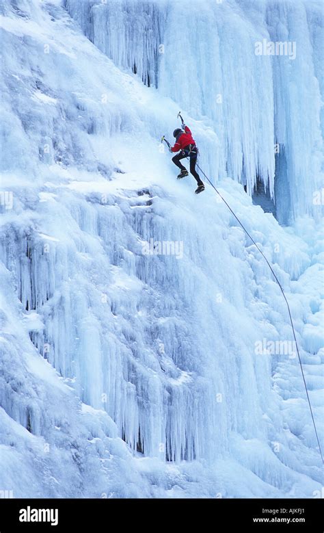 Grimpeur progressant sur une cascade de glace bleue spectaculaire