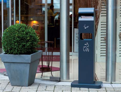 Photo d'un cendrier extérieur design placé sur une zone en pierre à côté d'une pelouse artificielle
