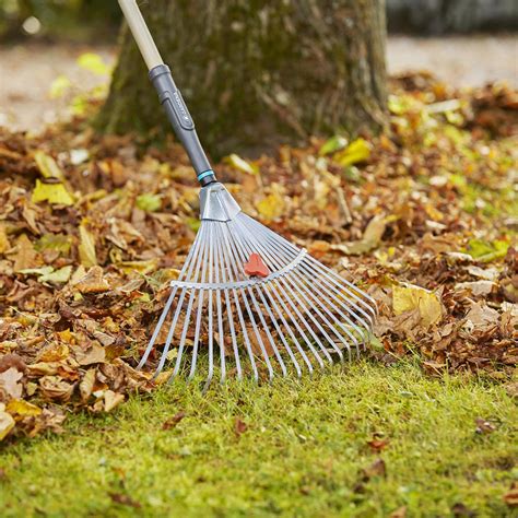 Personne utilisant un balai à gazon large pour ramasser des feuilles mortes