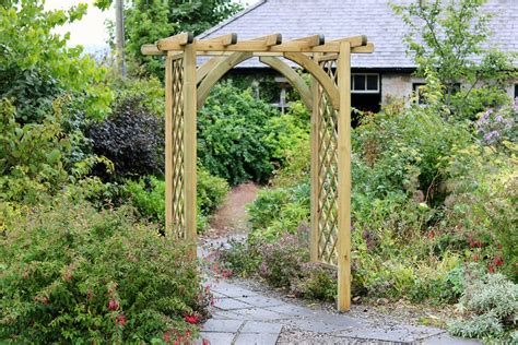Une arche de jardin en bois recouverte de fleurs de chèvrefeuille dans un jardin ensoleillé