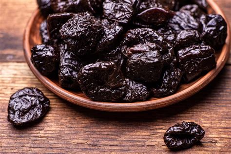 Photographie comparative : prunes fraîches sur l'arbre et pruneaux séchés prêts pour la consommation