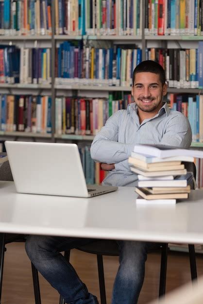 Étudiant travaillant dans une bibliothèque universitaire moderne avec des ressources numériques et physiques