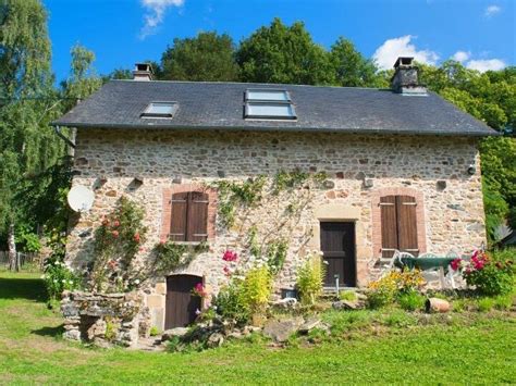 une façade de maison ancienne entièrement recouverte d'un feuillage de vigne vierge rouge flamboyant en automne