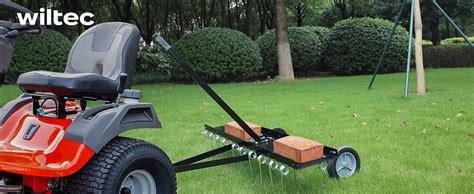 scarificateur tracté WilTec en action derrière un tracteur tondeuse