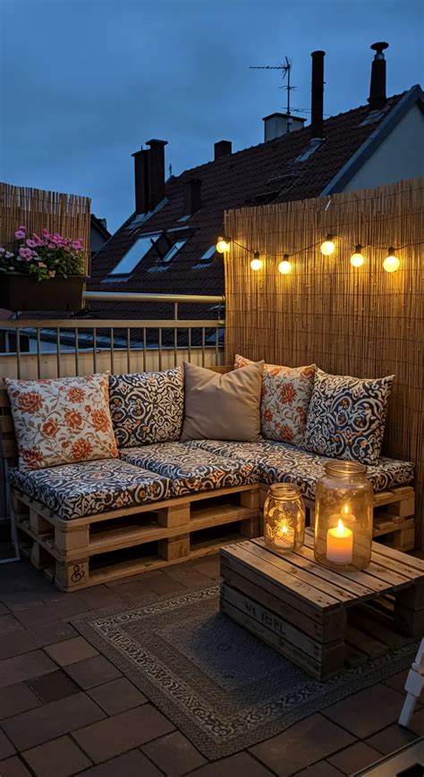 Photo d'une terrasse en palettes terminée avec coussins et guirlandes lumineuses
