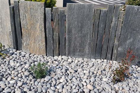 Vue d'ensemble d'un jardin contemporain utilisant l'ardoise sous différentes formes : paillage, dalles et palis verticaux