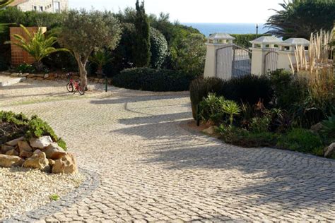 une allée de jardin bordée de pavés en pierre, avec des massifs de fleurs structurés