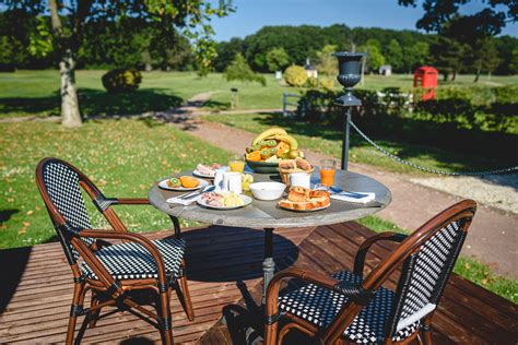 Petit-déjeuner continental servi sur une terrasse ensoleillée avec vue sur le jardin