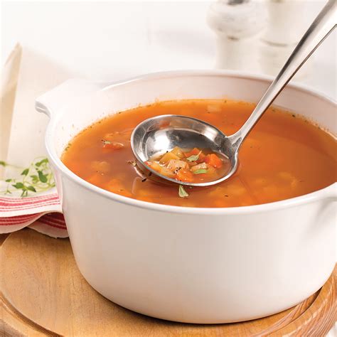 une louche plongeant dans une soupe de légumes fumante