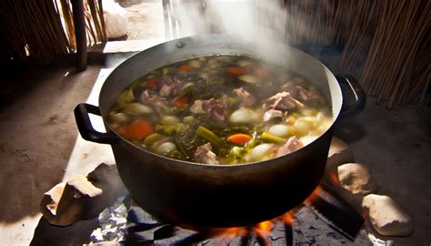 une marmite de bouillon de pot-au-feu mijotant doucement sur un feu de bois dans une cuisine rustique