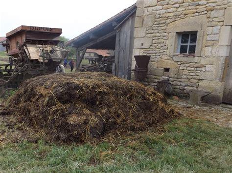 une ferme traditionnelle française avec un tas de fumier à proximité d'une maison de campagne