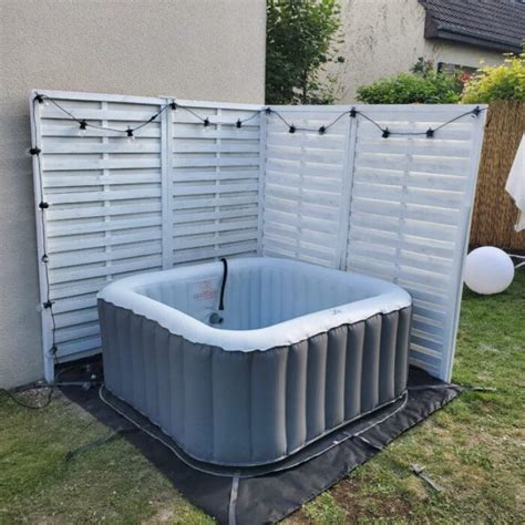 Installation d'un spa gonflable sur une surface préparée avec une bâche et des dalles de protection