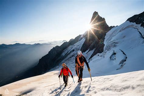 Photo d'un guide de montagne expliquant l'utilisation des coinceurs et des mousquetons à un élève sur un rocher école