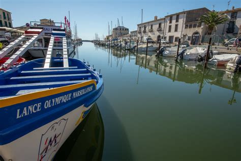 Vue panoramique du village de Marseillan avec ses quais animés et son port de plaisance sous un soleil méditerranéen