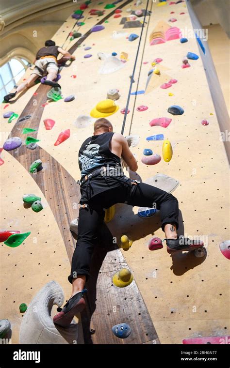 Un grimpeur en pleine ascension sur un bloc coloré dans une salle moderne