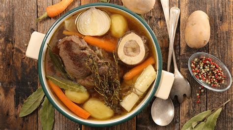 Photo d'une assiette creuse fumante de pot-au-feu, agrémentée de persil frais et accompagnée de fromage râpé.