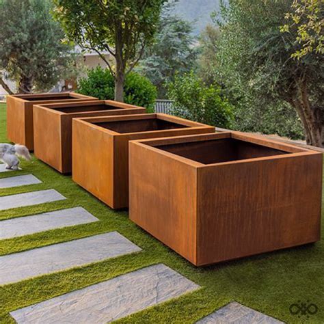 Une rangée de jardinières en acier Corten de différentes tailles installées sur une terrasse moderne