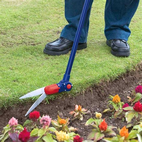 personne désherbant un jardin avec un outil à long manche