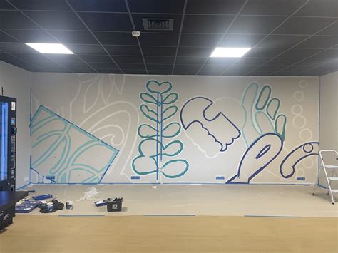 un artiste utilisant un marqueur Posca de grande taille pour réaliser une fresque murale abstraite