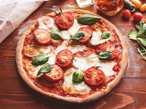 Une pizza italienne fraîchement préparée, coupée en parts sur une planche en bois, avec des ingrédients frais comme des tomates, du basilic et de la mozzarella fondante.