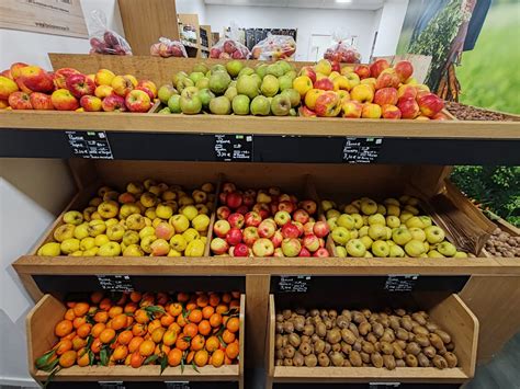 Vue intérieure d'un magasin de producteurs avec des étals abondants de fruits et légumes frais de saison.