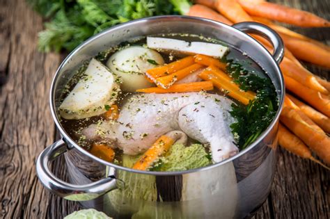 une marmite traditionnelle remplie d'un bouillon de volaille doré avec des légumes frais et des herbes aromatiques