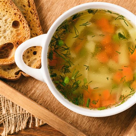 un bol de bouillon de poule fumant avec des vermicelles et des herbes fraîches