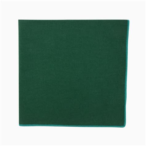 détail d'une pochette de costume vert lierre insérée dans une poche de veste en loden