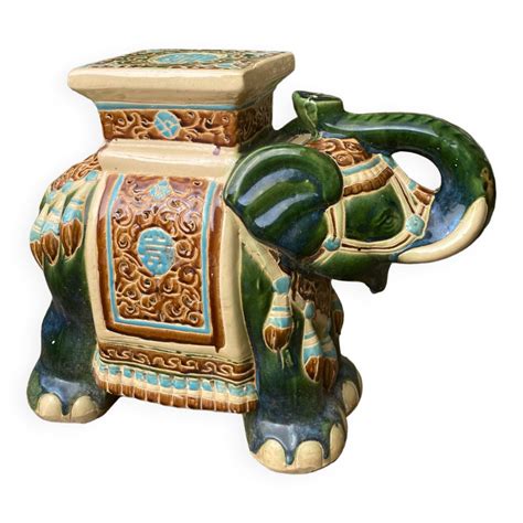 Un élégant éléphant en céramique bleu portant une succulente sur une étagère en bois clair avec une ambiance zen