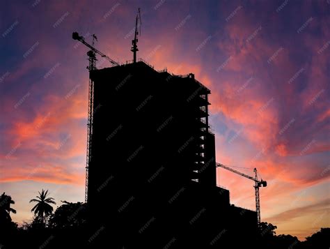 une silhouette d'une grue de construction surplombant un paysage urbain au crépuscule