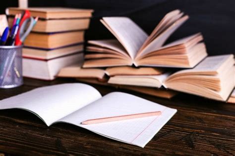 Une pile de cahiers et de livres ouverts sur un bureau, symbolisant l'étude et la préparation.