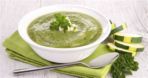 Bol de potage de courgettes au curry, une moitié chaude fumante, l'autre moitié froide avec des glaçons