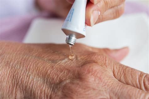 Gros plan sur une main appliquant une noisette de crème onctueuse, mettant en valeur la texture légère et non grasse