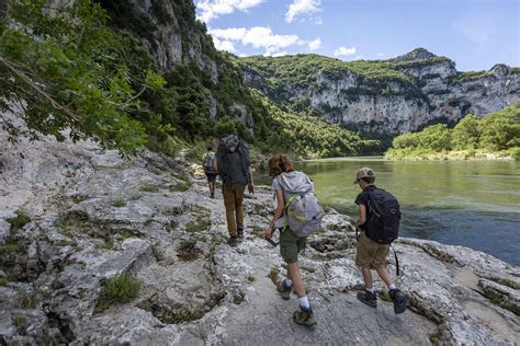 Randonnée le long d'une rivière en Ardèche avec des falaises en arrière-plan