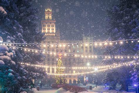 Un sapin de Noël illuminé dans une place de village enneigée