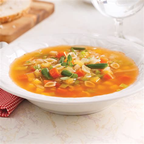 une assiette de soupe fumante aux légumes racines avec une touche de crème et des herbes fraîches