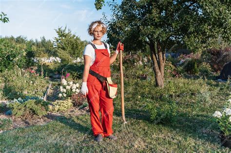 une femme jardinière portant des bottes élégantes dans un jardin fleuri