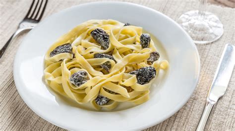 Photographie d'une assiette de pâtes fraîches aux morilles servies dans une ancienne salle de fruitière