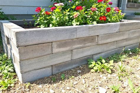 une jardinière en ciment en forme de barque avec une texture évoquant l'écorce de bois, disposée sur une table en bois clair