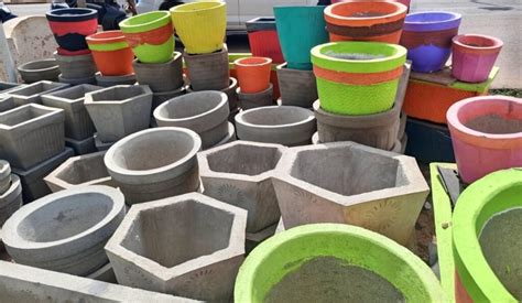 une sélection de petits pots en ciment aux formes variées, disposés sur une étagère en bois