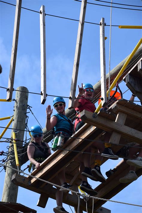 Personnes portant des harnais d'accrobranche et des casques, prêtes à commencer un parcours