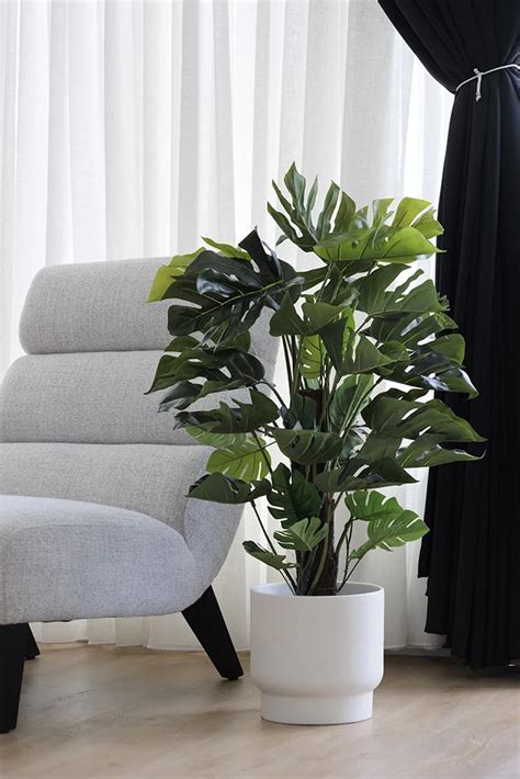 un grand monstera artificiel placé dans un cache-pot design
