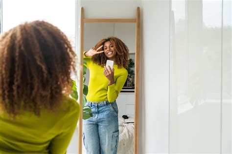 Une personne devant un miroir, ajustant une coupe courte et moderne, symbolisant le changement et l'affirmation de soi.