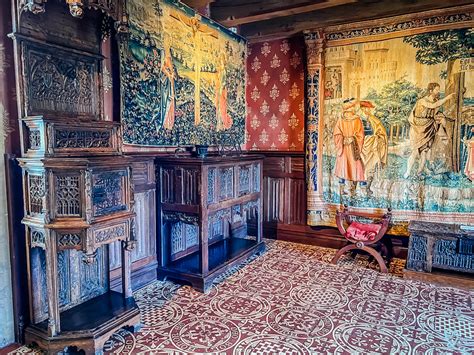 une salle de château médiéval avec tapisseries et mobilier en bois sombre