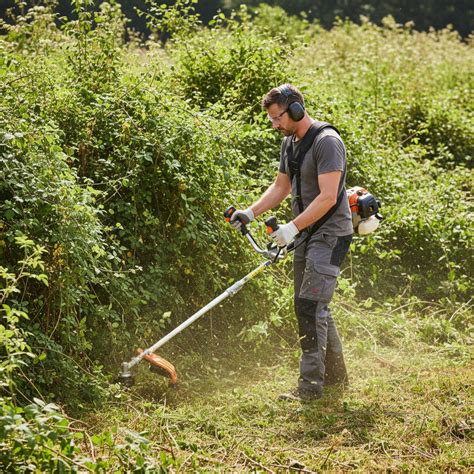 une débroussailleuse en action sur un terrain envahi par la végétation
