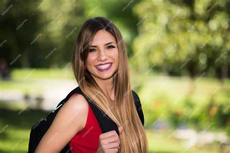 Jeune femme souriante dans un jardin, avec des outils de jardinage à côté d'elle