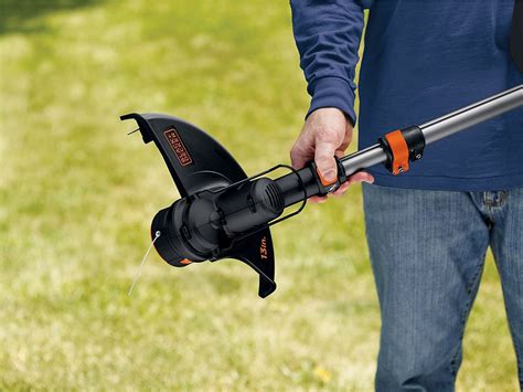 Un coupe-bordures Black & Decker en action, taillant l'herbe le long d'une bordure de jardin