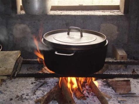 une marmite traditionnelle en fonte sur un feu de bois, évoquant les techniques culinaires anciennes
